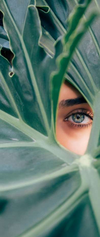 Eine Frau schaut mit einem Auge durch ein Blatt